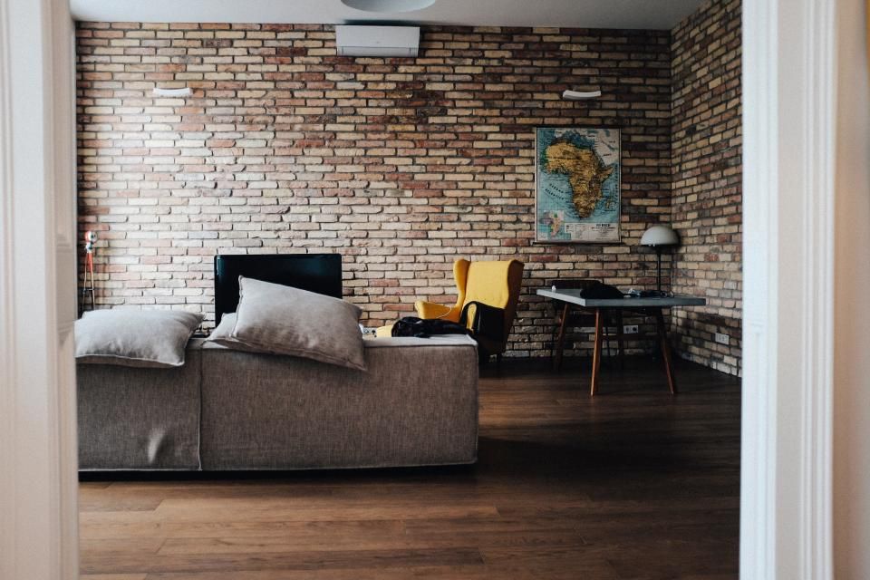 Hall with a brick wall and a grey sofa